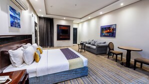 A hotel room with a bed, a sofa, a small table, and a chair. - Taleen Serviced Apartments Granada (Riyadh)