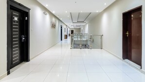 A hallway with a glass railing, a staircase, and a door with a lock. - Taleen Serviced Apartments Granada (Riyadh)