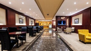 A hotel lobby with a marble floor, leather seating, a reception desk, and a television. - Taleen Serviced Apartments Granada (Riyadh)