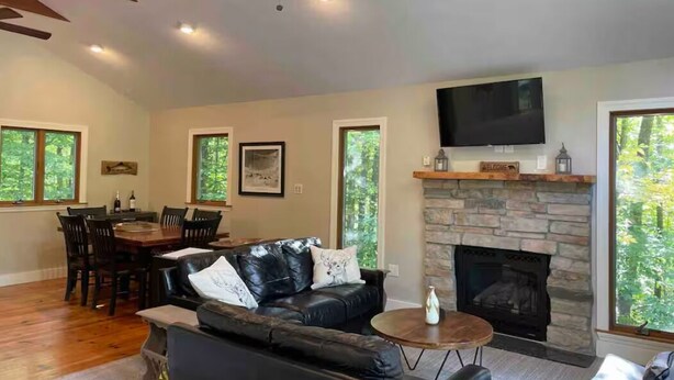 Amplia sala de estar con chimenea, un televisor montado encima y una zona de comedor con mesa y sillas.