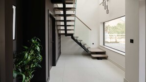 A modern interior with a staircase, a plant, and a large window. - Woldside - Luxury Property Sleeps 10 (York)