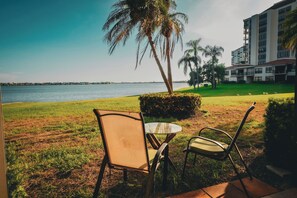 A patio with a table and chairs overlooking a body of water, with a building in the background. - Waterfront Oasis on Isla Del Sol in Bahia Del Mar (St. Petersburg)