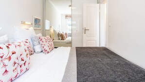 Ein Hotelzimmer mit einem Bett, einem Nachttisch, einem Spiegel und einer Tür zu einem weiteren Raum.