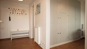 En hall med ett element, en bänk, ett väggmonterat kroksystem och en uppsättning vita skåp.