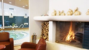 Una habitación con chimenea, piscina y sillones de cuero.