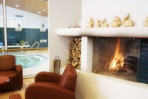 A room with a fireplace, a pool, and leather chairs.
