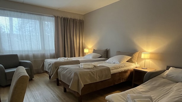 Habitación de hotel con dos camas, un sofá, un escritorio y una lámpara.