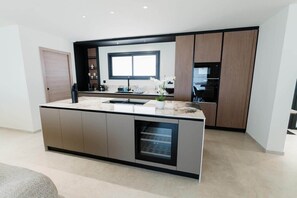 Eine moderne Küche mit Kochinsel, integrierten Geräten und einem großen Fenster.