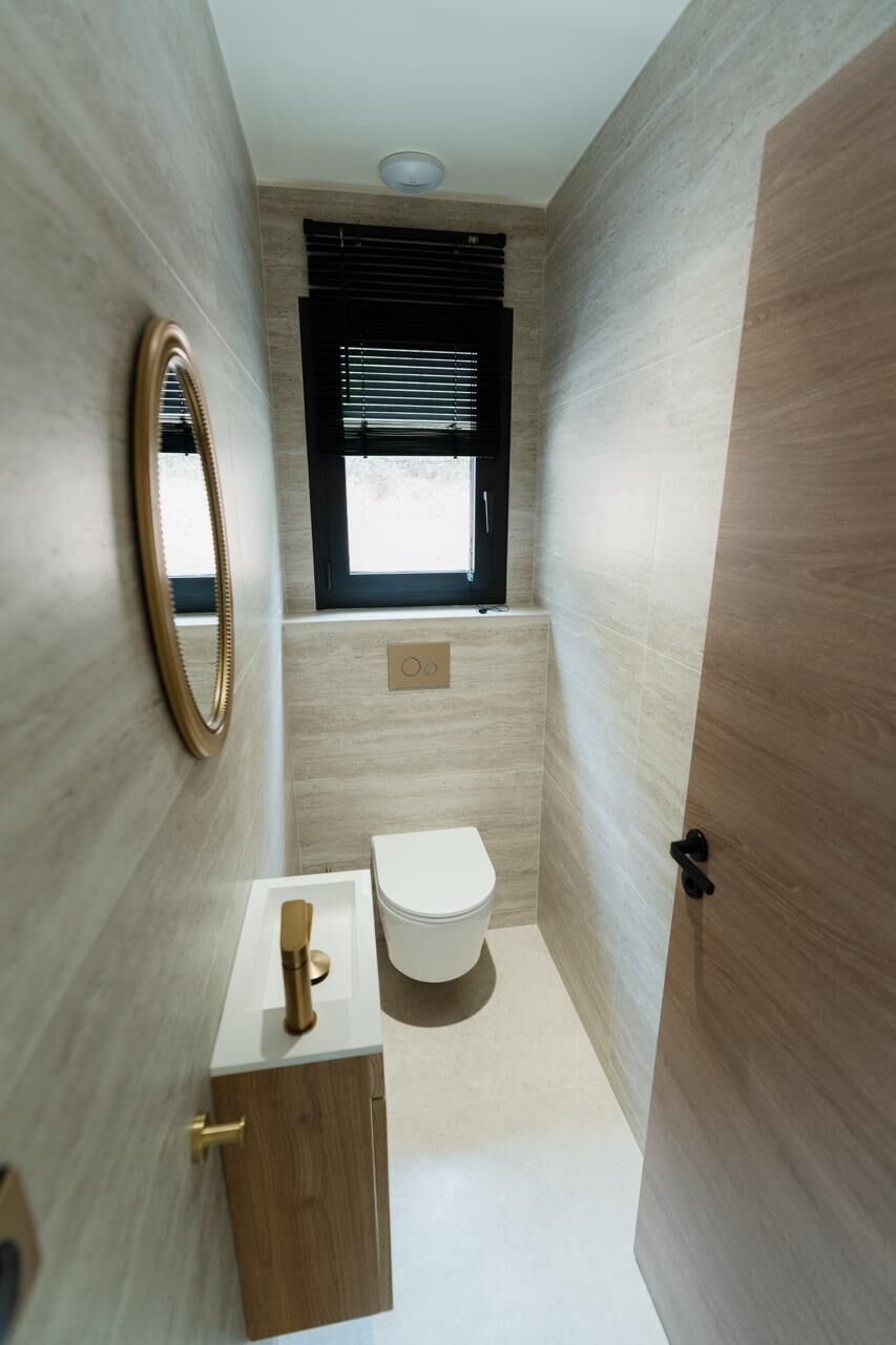 A compact bathroom with a toilet, sink, and mirror.