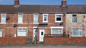 A row of terraced houses with brick facades, white-framed windows, and satellite dishes. - Vacant nests | The Cowpen | 3BR | Parking & Wi-Fi (Blyth)