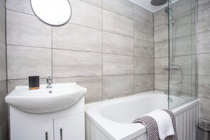 A modern bathroom with a white sink, a glass shower enclosure, and a towel on the tub. - Vacant nests | The Cowpen | 3BR | Parking & Wi-Fi (Blyth)