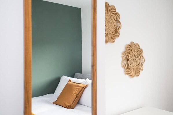 A bedroom with a bed, pillows, and a green wall.