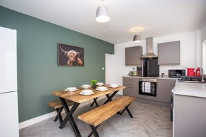 A modern kitchen with a dining table, benches, and a microwave.