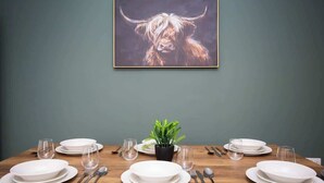 A dining table set with plates, glasses, cutlery, and a potted plant. - Vacant nests | The Cowpen | 3BR | Parking & Wi-Fi (Blyth)