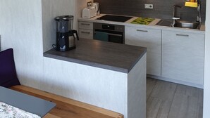 Une cuisine moderne avec des meubles gris, une machine à café noire, un grille-pain et un évier.