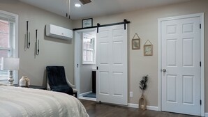 Een slaapkamer met een bed, een stoel, een schuifdeur, een wandairconditioner en een raam.