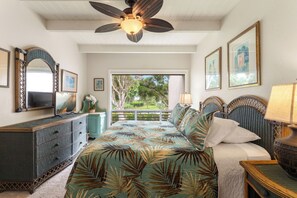 Ein Schlafzimmer mit Bett, Kommode, Deckenventilator und Bildern an den Wänden.