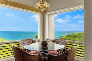 Ein Tisch mit Glasplatte, vier Korbstühle, eine Schale und Blick auf das Meer.