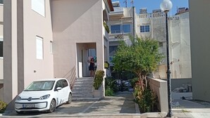 A residential building with a white car parked in the driveway, a clear sky, and a staircase leading to the entrance. -  30m² studio 90m from the beach in Chania Self Check‑in Parking Garden Fast WiFi (Chania)
