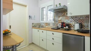 A kitchen with a wooden countertop, white cabinets, a stainless steel dishwasher, and a window with a view. -  30m² studio 90m from the beach in Chania Self Check‑in Parking Garden Fast WiFi (Chania)