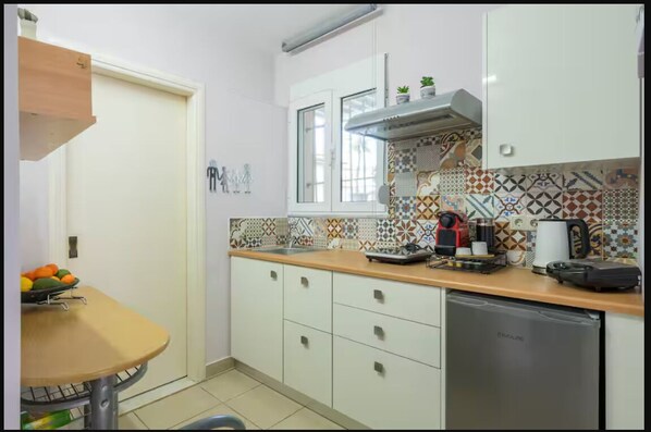 A kitchen with a wooden countertop, white cabinets, a stainless steel dishwasher, and a window with a view. -  30m² studio 90m from the beach in Chania Self Check‑in Parking Garden Fast WiFi (Chania)
