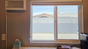 Ein Zimmer mit Fenster, Wandklimaanlage, Taschentuchbox und einem kleinen Tisch mit Gegenständen.