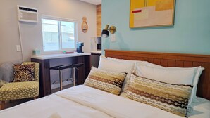 Ein Hotelzimmer mit Bett, Schreibtisch, Stuhl, einer Kaffeemaschine und einem Fenster.