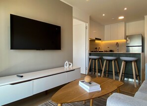 Een moderne woonkamer met een flatscreen televisie, een houten salontafel en een bank.