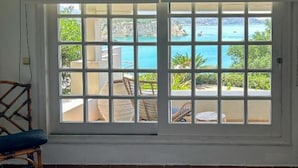 A hotel room with a large window overlooking a pool and outdoor seating. - Crete Beachfront Coconut Gem With Seaviews Pool (Apokoronas)