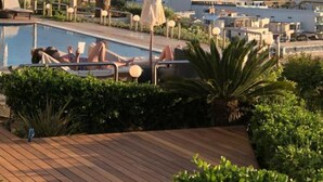 A pool area with lounge chairs and umbrellas, surrounded by greenery and overlooking a mountainous landscape. - Crete Beachfront Coconut Gem With Seaviews Pool (Apokoronas)