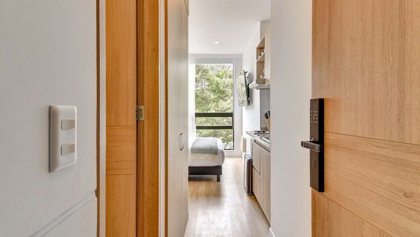A narrow hallway leading to a bedroom with a bed, a window, and a kitchenette. - w Amazing Loft in the Heart of Chico Norte (Bogotá)