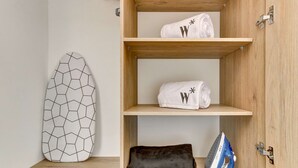 A room with a wooden shelf unit, an ironing board, and a rolled-up towel. - w Amazing Loft in the Heart of Chico Norte (Bogotá)