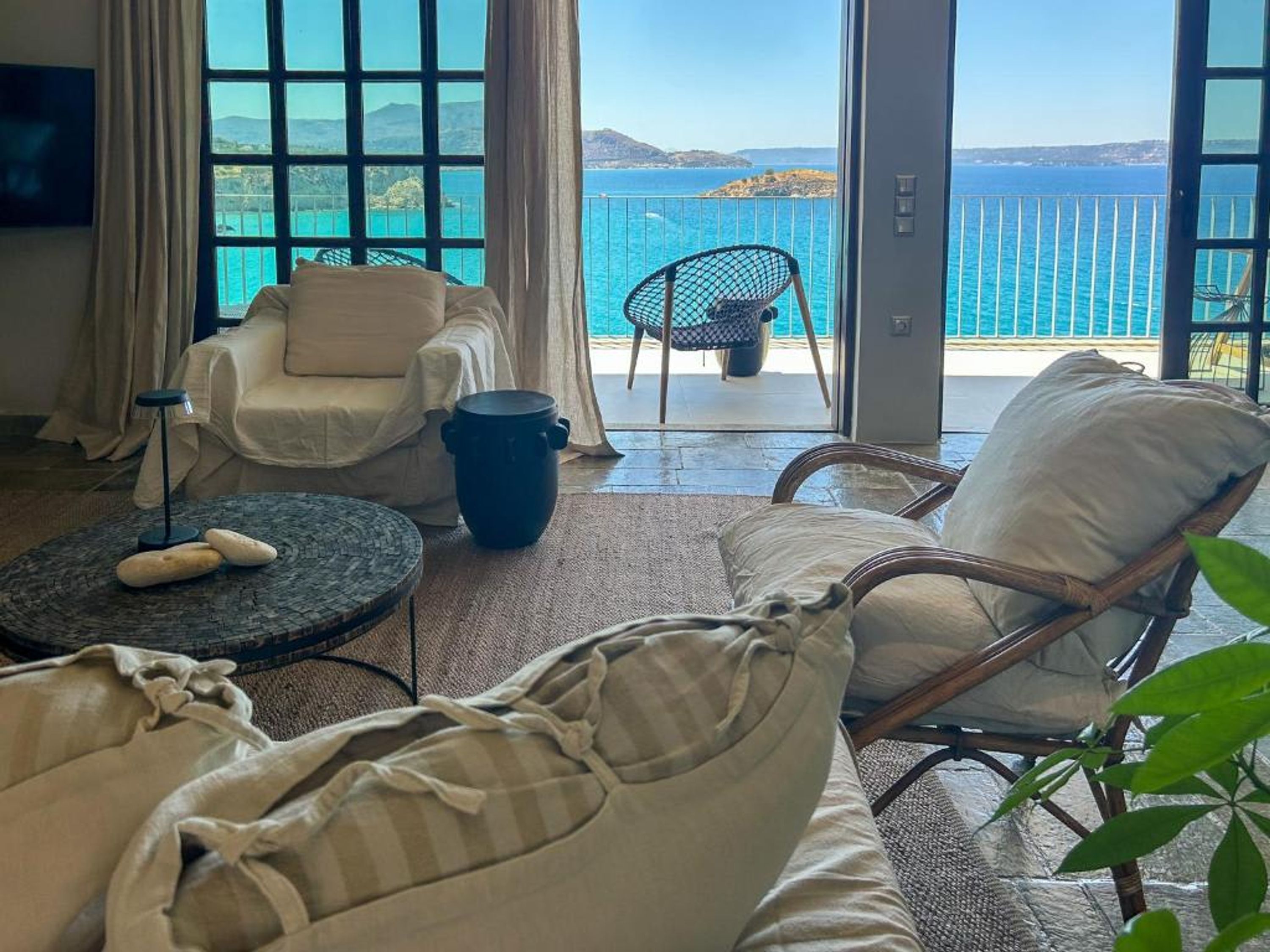 Une pièce avec vue sur la mer, comprenant un canapé, un fauteuil, une table et une grande fenêtre.