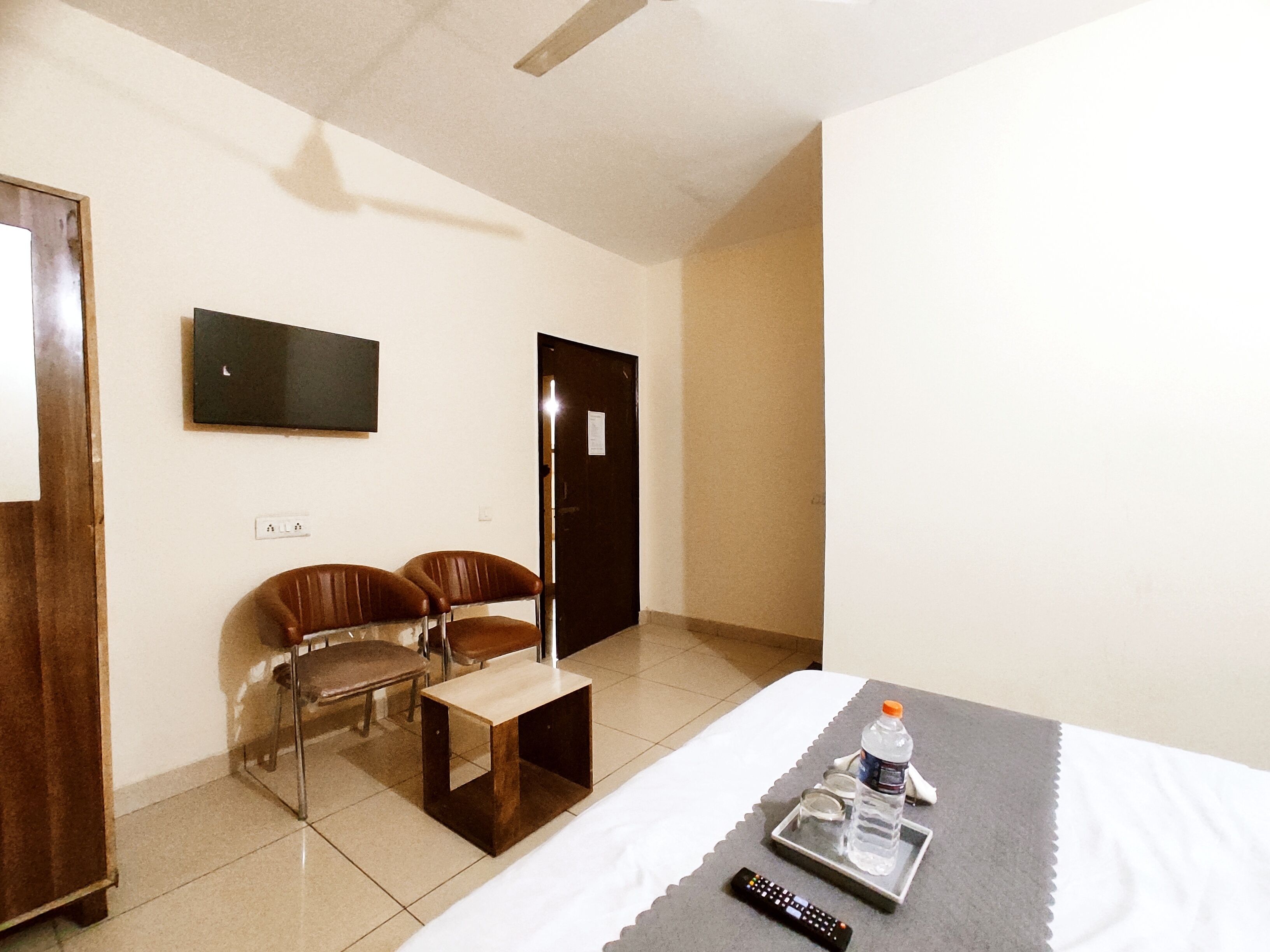 Une chambre d’hôtel avec un lit, une petite table, deux chaises, un téléviseur fixé au mur et une porte.