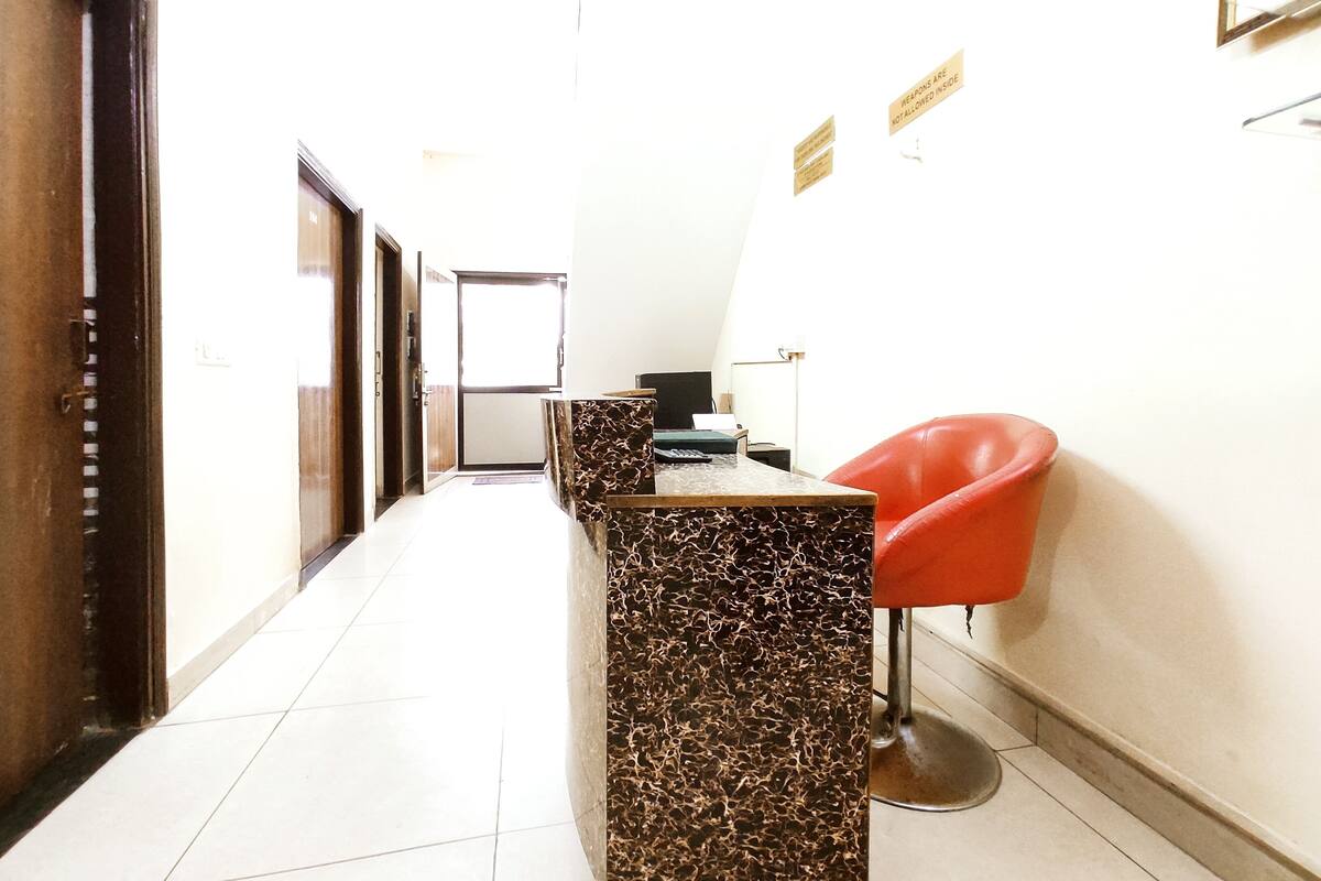 A hallway with a reception desk, a red chair, and a door.