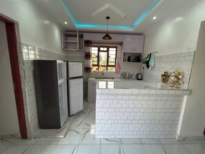 A modern kitchen with white tiled walls, a central island, and built-in appliances. - The PentHouse (Rungiri)