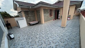 Ein modernes Haus mit gefliester Terrasse, einer Badewanne und einer kleinen Sitzgelegenheit im Freien.