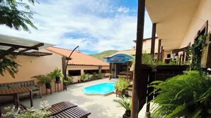 A pool area with a wooden deck, lounge chairs, and potted plants. - Flamboyant Space - Armação dos Búzios - Near the Beach (Armação dos Búzios)