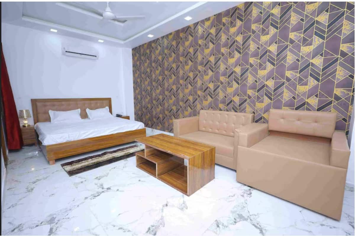 Un dormitorio con cama, sofá, mesita de centro y pared decorada.