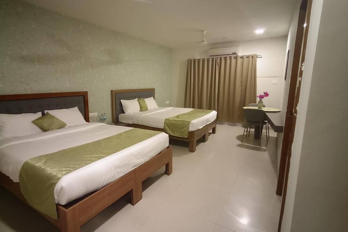 Habitació d'hotel amb dos llits, una taula petita i una cadira.