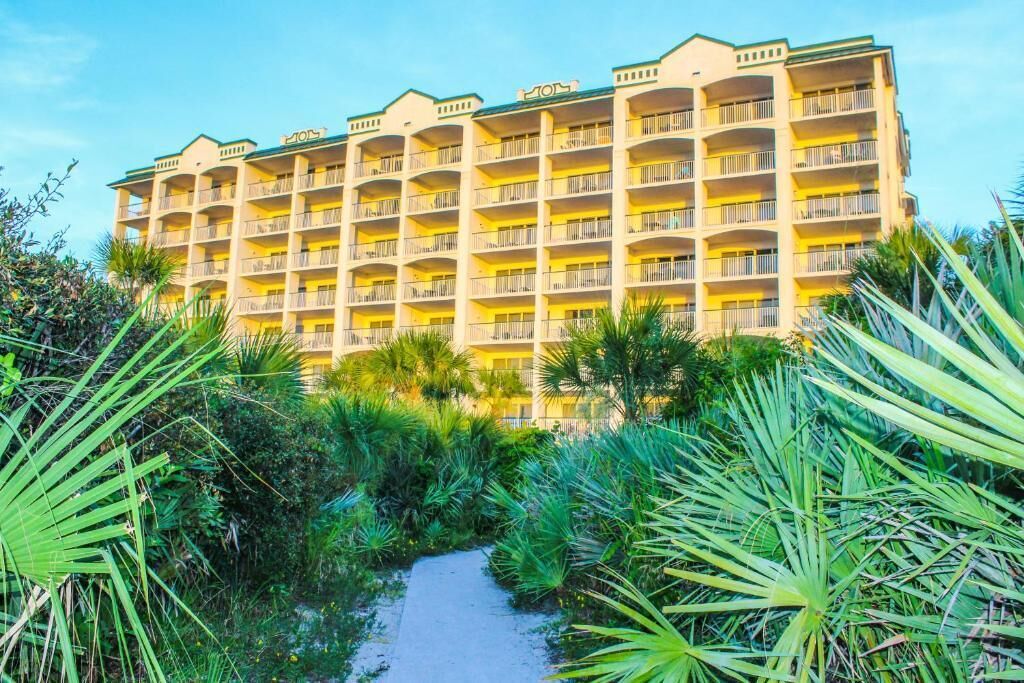 Un hôtel à plusieurs étages, doté de balcons et entouré d’une végétation tropicale.