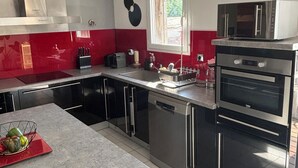 Une cuisine moderne dotée d’appareils électroménagers en acier inoxydable, d’un crédence rouge et blanche et d’une fenêtre laissant entrer la lumière naturelle.