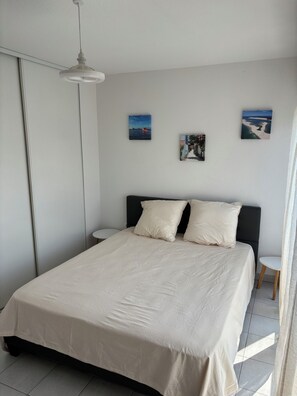 Ein Schlafzimmer mit einem Bett, einem Nachttisch, einer Wandleuchte und zwei gerahmten Bildern.