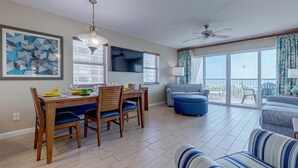A dining area with a wooden table and chairs, a chandelier, and a large window with blinds. - Charming 2-bedroom apartment with AC in wonderful Cocoa Beach (Cocoa Beach)