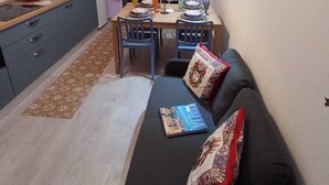 Ett kompakt bostadsutrymme med ett litet kök, matplats och sittgrupp.