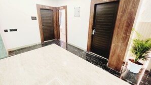 Un couloir avec deux portes portant les numéros 303 et 304, une plante en pot et un sol en marbre.