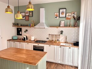A modern kitchen with white cabinetry, a wooden countertop, hanging pendant lights, and various kitchen utensils. - Spacious apartment in the heart of Umbria, for families and trips with friends. (Torgiano)