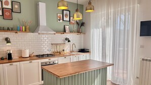 Una cocina moderna con una isla central, luces colgantes y una variedad de electrodomésticos.