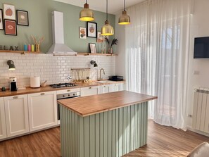 A modern kitchen with a central island, pendant lights, and a variety of kitchen appliances. - Spacious apartment in the heart of Umbria, for families and trips with friends. (Torgiano)