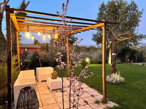 A covered outdoor seating area with a pergola, string lights, and a small table with a plant. - Spacious apartment in the heart of Umbria, for families and trips with friends. (Torgiano)
